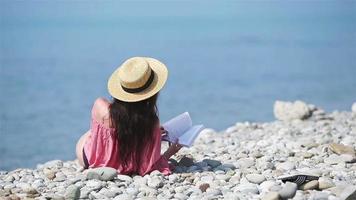 Young woman reading book during tropical white beach video