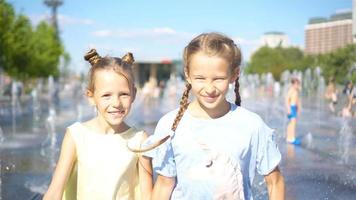 Little adorable girls have fun in street fountain at hot sunny day video