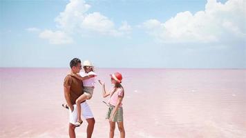 família caminha em um lago de sal rosa em um dia ensolarado de verão. video