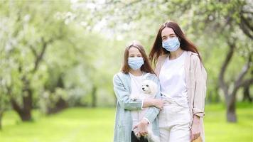 familie van moeder en dochter in bloeiend kers tuin in maskers video