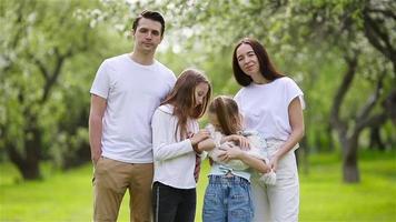 família adorável no jardim cerejeira florescendo em lindo dia de primavera video