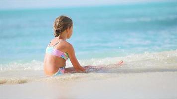 Adorable little girl sitting on white snow sand video