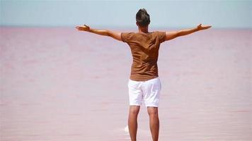 un turista camina en un lago de sal rosa en un día soleado de verano. video