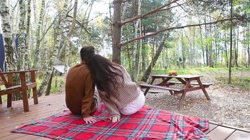 jovem casal sentado em a terraço a outono floresta video