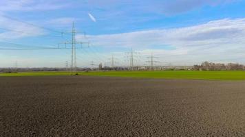 Drone video of a flight along a power line towards a substation during daytime