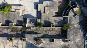 Vertical ascent drone video of a ruin of a luxury hotel on a tropical beach after destruction by a hurricane