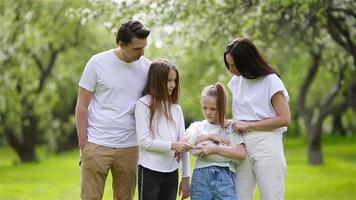 adorabile famiglia nel fioritura ciliegia giardino su bellissimo primavera giorno video