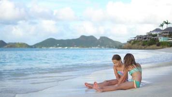 Two little happy girls have a lot of fun at tropical beach playing together with sand video