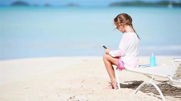 Little girl making video or photo with by her camera sitting on the sunbed