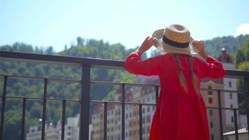 Little girl at hat on the embankment of a mountain river in a European city. video