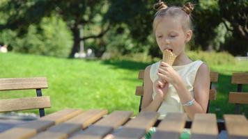 poco ragazza mangiare gelato all'aperto a estate nel all'aperto bar video