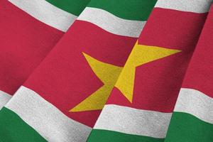 Suriname flag with big folds waving close up under the studio light indoors. The official symbols and colors in banner photo