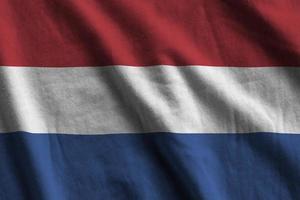 Netherlands flag with big folds waving close up under the studio light indoors. The official symbols and colors in banner photo