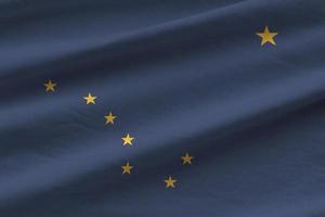 Alaska US state flag with big folds waving close up under the studio light indoors. The official symbols and colors in banner photo