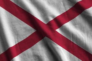 Alabama US state flag with big folds waving close up under the studio light indoors. The official symbols and colors in banner photo