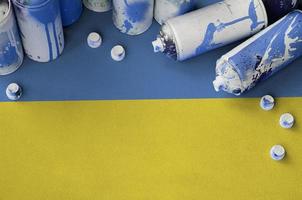 Ukraine flag and few used aerosol spray cans for graffiti painting. Street art culture concept photo