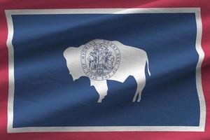 Wyoming US state flag with big folds waving close up under the studio light indoors. The official symbols and colors in banner photo