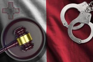 Malta flag with judge mallet and handcuffs in dark room. Concept of criminal and punishment, background for judgement topics photo