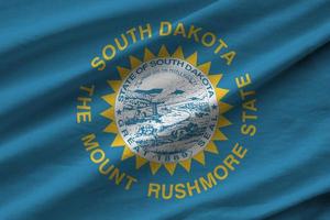 South Dakota US state flag with big folds waving close up under the studio light indoors. The official symbols and colors in banner photo