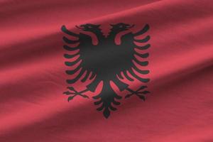 Albania flag with big folds waving close up under the studio light indoors. The official symbols and colors in banner photo