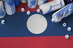 Laos flag and few used aerosol spray cans for graffiti painting. Street art culture concept photo
