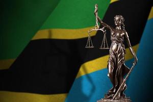 Tanzania flag with statue of lady justice and judicial scales in dark room. Concept of judgement and punishment photo