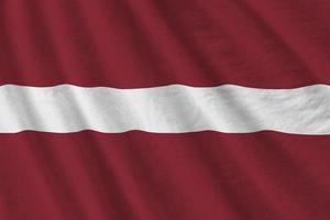 Latvia flag with big folds waving close up under the studio light indoors. The official symbols and colors in banner photo