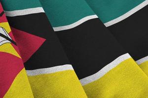 Mozambique flag with big folds waving close up under the studio light indoors. The official symbols and colors in banner photo