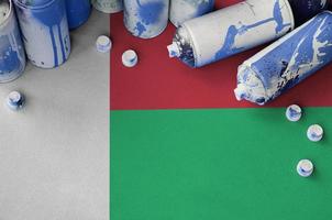Madagascar flag and few used aerosol spray cans for graffiti painting. Street art culture concept photo