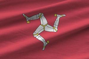 Isle of Man flag with big folds waving close up under the studio light indoors. The official symbols and colors in banner photo