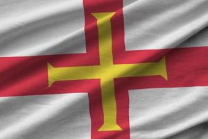 Guernsey flag with big folds waving close up under the studio light indoors. The official symbols and colors in banner photo