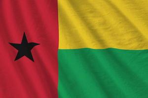 Guinea Bissau flag with big folds waving close up under the studio light indoors. The official symbols and colors in banner photo