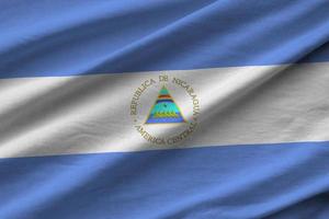 bandera de nicaragua con grandes pliegues ondeando de cerca bajo la luz del estudio en el interior. los símbolos y colores oficiales en banner foto