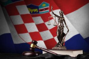 Croatia flag with statue of lady justice, constitution and judge hammer on black drapery. Concept of judgement and guilt photo