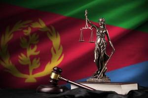 Eritrea flag with statue of lady justice, constitution and judge hammer on black drapery. Concept of judgement and guilt photo
