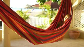 Adorable little girl on tropical vacation relaxing in hammock video