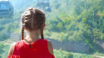 adorabile contento poco ragazza nel il cabina su il cavo auto nel montagne nel il sfondo di beautful paesaggio video