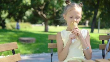 poco ragazza mangiare gelato all'aperto a estate nel all'aperto bar video