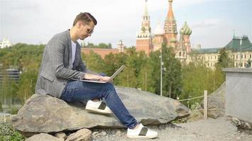 el hombre está trabajando con una laptop mientras se relaja en el parque video