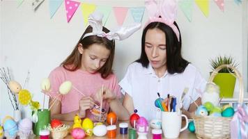 madre y su pequeña hija pintando huevos. familia feliz preparándose para pascua. video