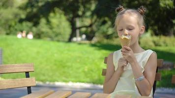 poco ragazza mangiare gelato all'aperto a estate nel all'aperto bar video