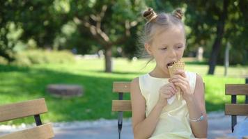 poco ragazza mangiare gelato all'aperto a estate nel all'aperto bar video