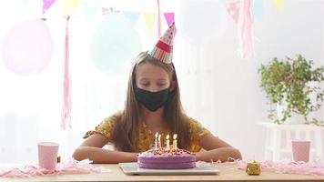 Caucasian girl is dreamily smiling and looking at birthday rainbow cake. Festive colorful background with balloons. Birthday party and wishes concept. video