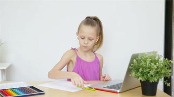echt schoolmeisje zittend Bij tafel met laptop en leerboek en aan het doen huiswerk. video