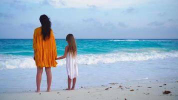 Little adorable girl and young mother at tropical beach in warm evening video