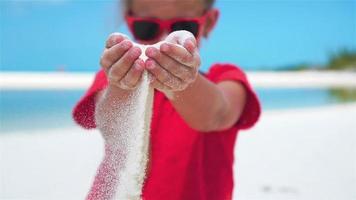 Little girl playing with beautiful white sand at tropical beach. SLOW MOTION video