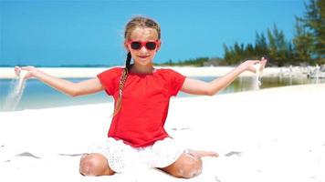 liten flicka spelar med skön vit sand på tropisk strand. långsam rörelse video