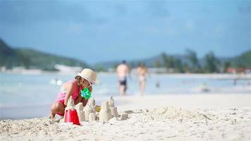 wenig Mädchen beim tropisch Strand Herstellung Sand Schloss video