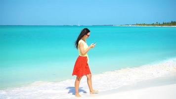 giovane donna uso Telefono durante tropicale spiaggia vacanza. turista utilizzando mobile smartphone. video