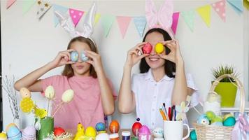 mãe e sua filha pintando ovos. família feliz se preparando para a páscoa. video